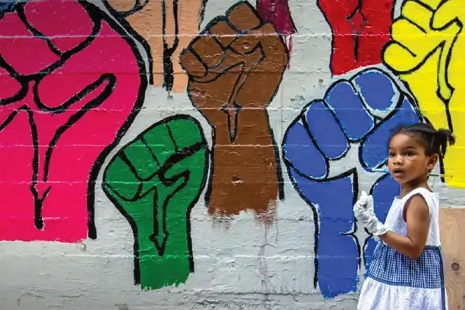 Young Black girl looks at mural of colorful painted upraised fists